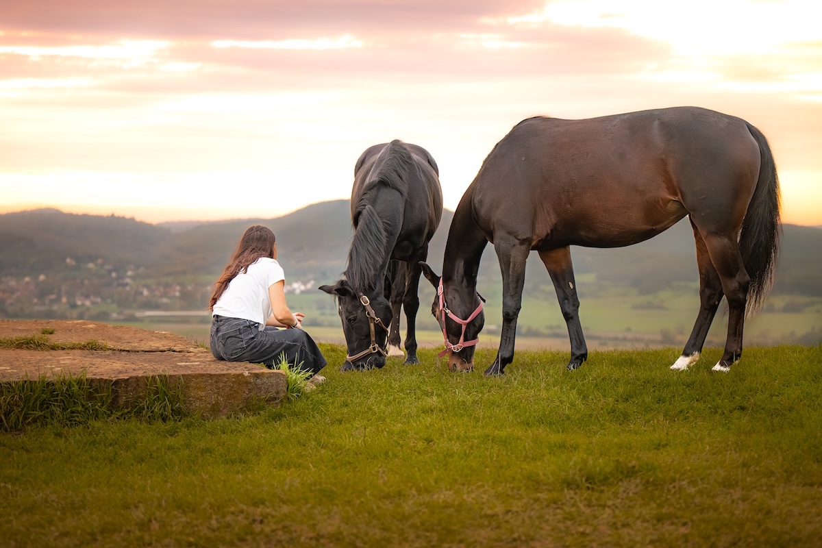 Jeune femme laissant ses chevaux brouter l'herbe calmement