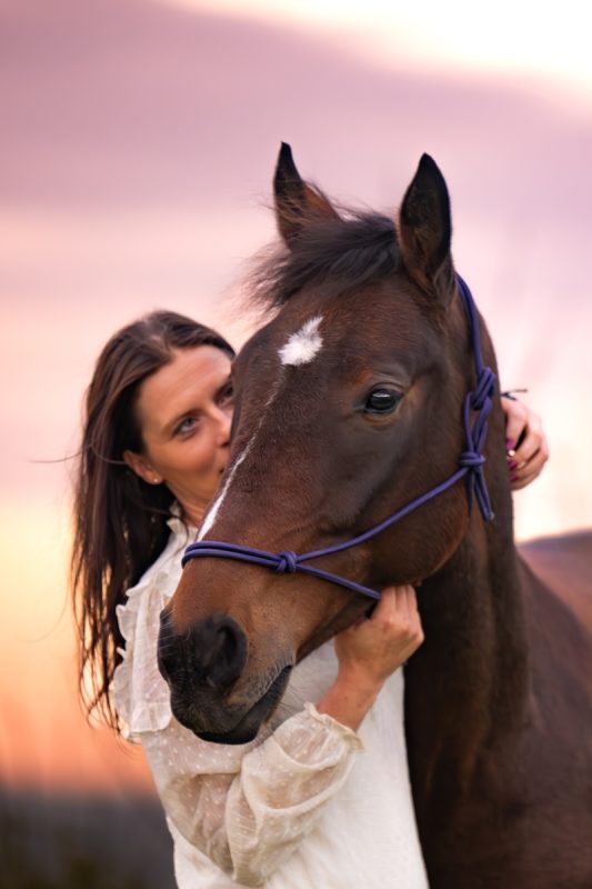 Praticienne en bien-être animal posant un regard bienveillant sur un cheval
